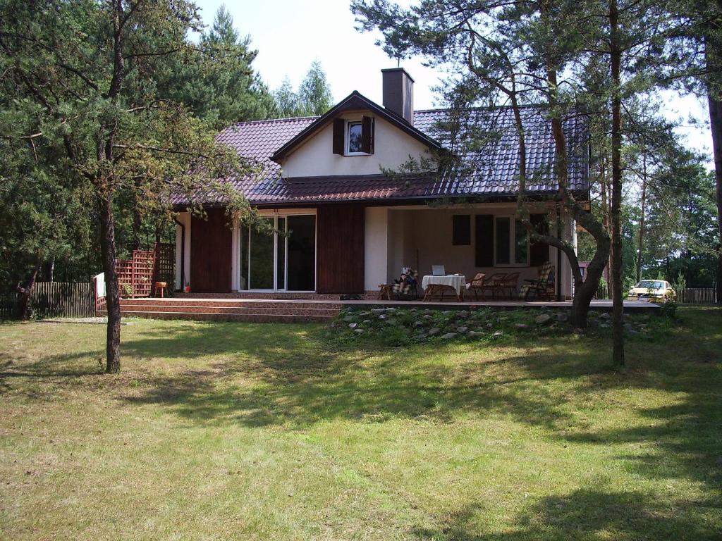 une maison avec une terrasse couverte et une cour dans l'établissement Domek nad Narwią, à Długosiodło