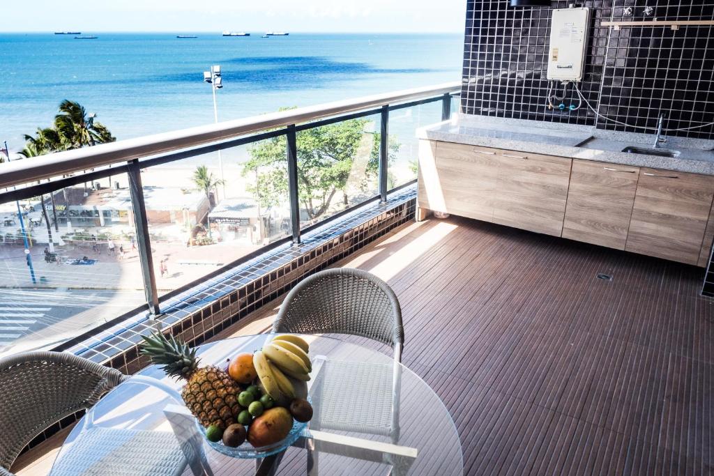 una mesa con un bol de fruta en el balcón con vistas a la playa en LANDSCAPE - FVP Group, en Fortaleza