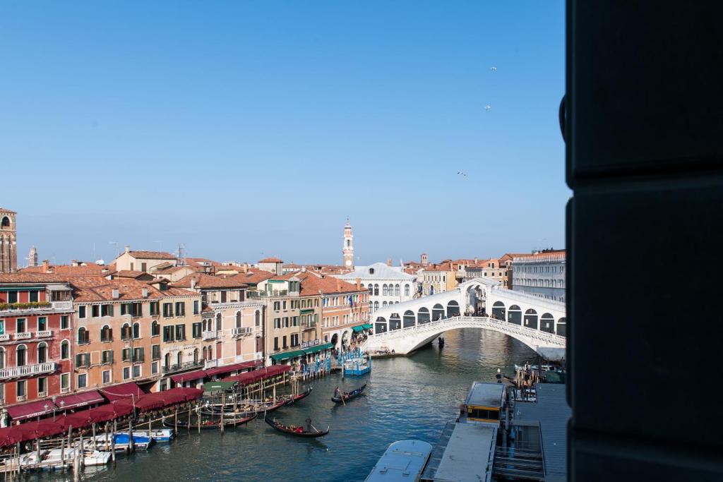 a bridge over a river in a city with boats at Palazzo Bembo - Exclusive Accommodation in Venice