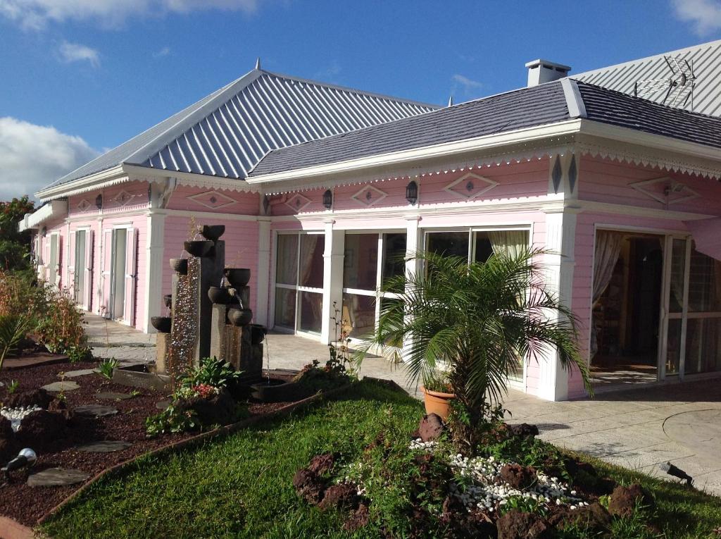 een roze huis met een palmboom in de tuin bij L'ECHELLE in La Plaine des Palmistes