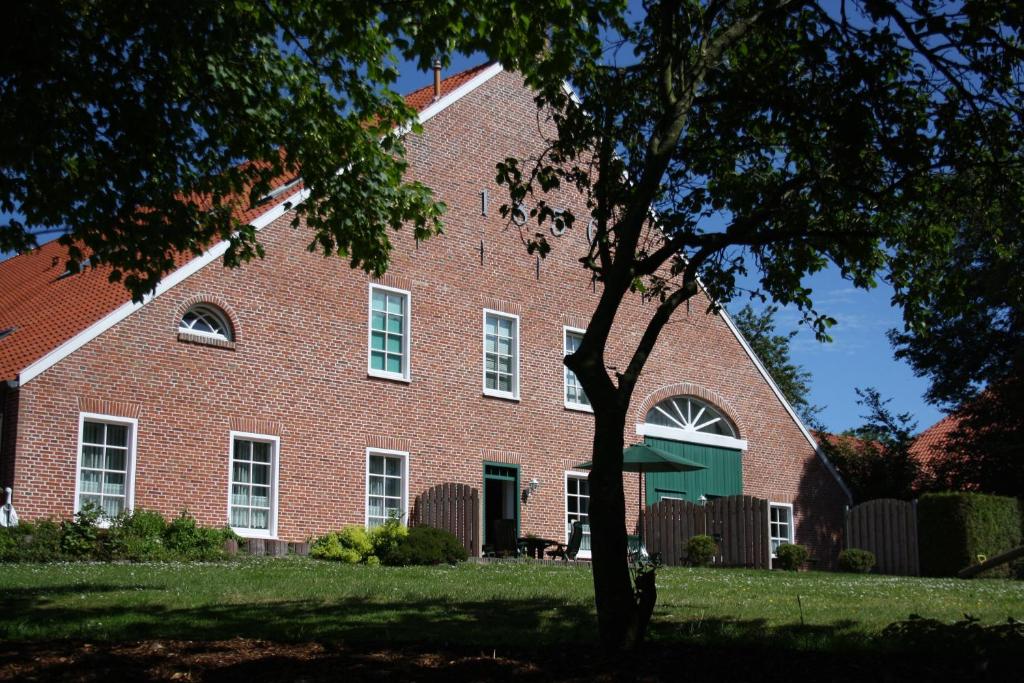 a red brick building with a tree in front of it at Gulfhof Greetsiel in Greetsiel