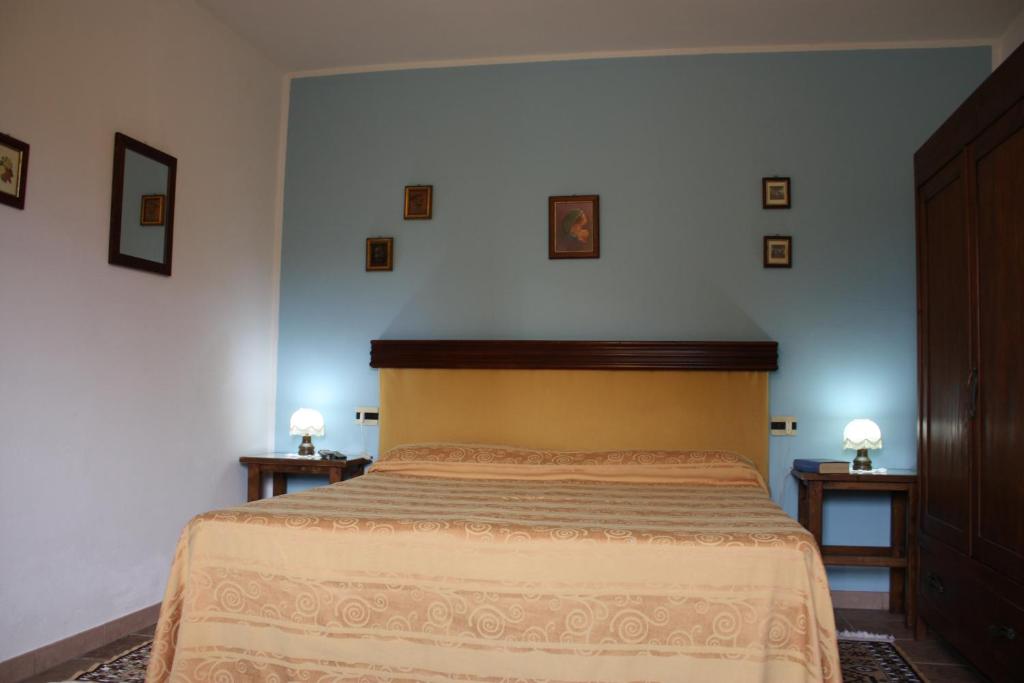 um quarto com uma cama com duas mesas de cabeceira e dois candeeiros em Agriturismo Magnaboschi em Alberese