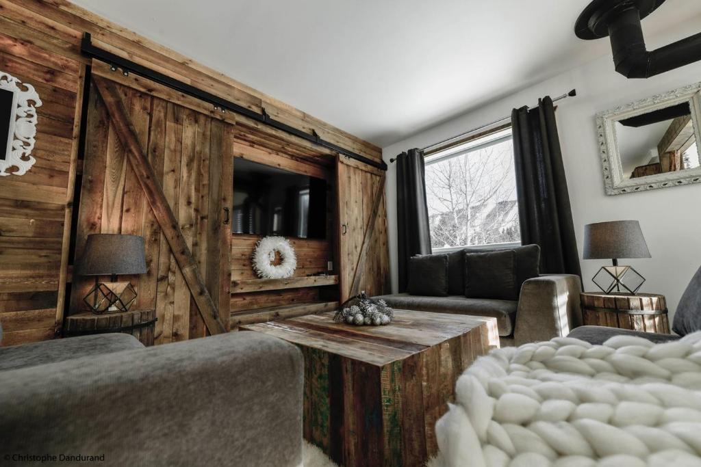 a bedroom with a wooden wall with a sliding barn door at Le Vanilee - Les Chalets Spa Canada in La Malbaie