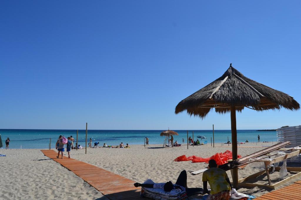 プンタ・プロシュートにあるVilla Luana Punta Prosciuttoの藁傘を持つ浜