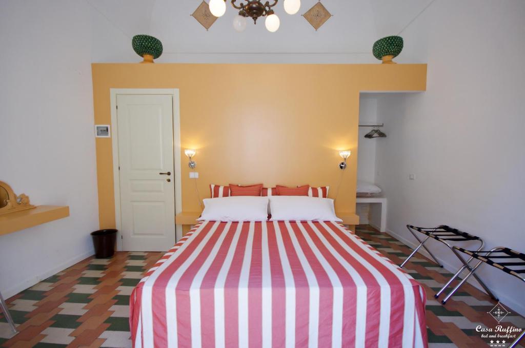 a bedroom with a bed with a red and white striped sheets at B&B Casa Ruffino in Balestrate