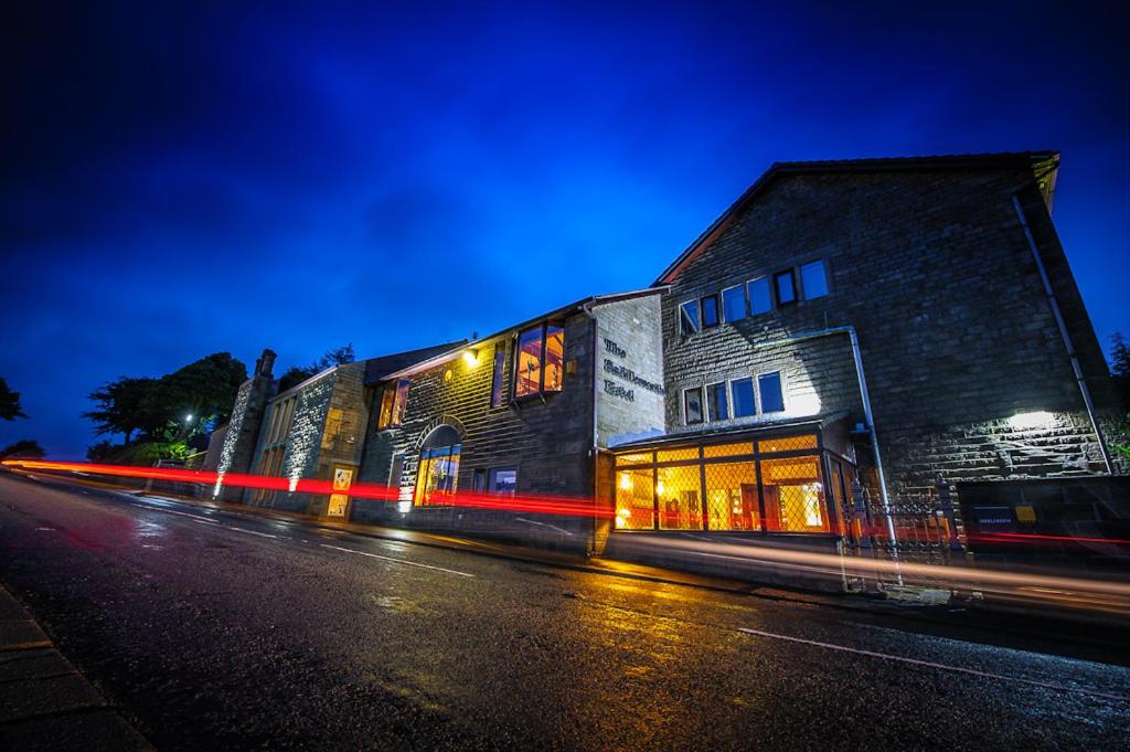 a building on the side of a street at night at The Saddleworth Hotel in Diggle