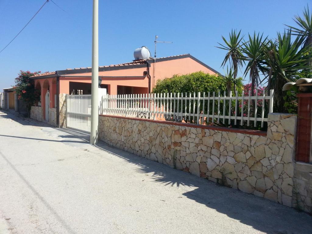 une clôture blanche sur un mur en pierre à côté d'une maison dans l'établissement Casa di Lory a Bruca, à Scicli