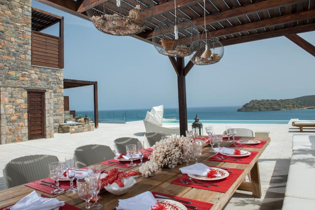 a wooden table with plates and glasses on a patio at Villa Danae by Elounda Island View Villas in Elounda