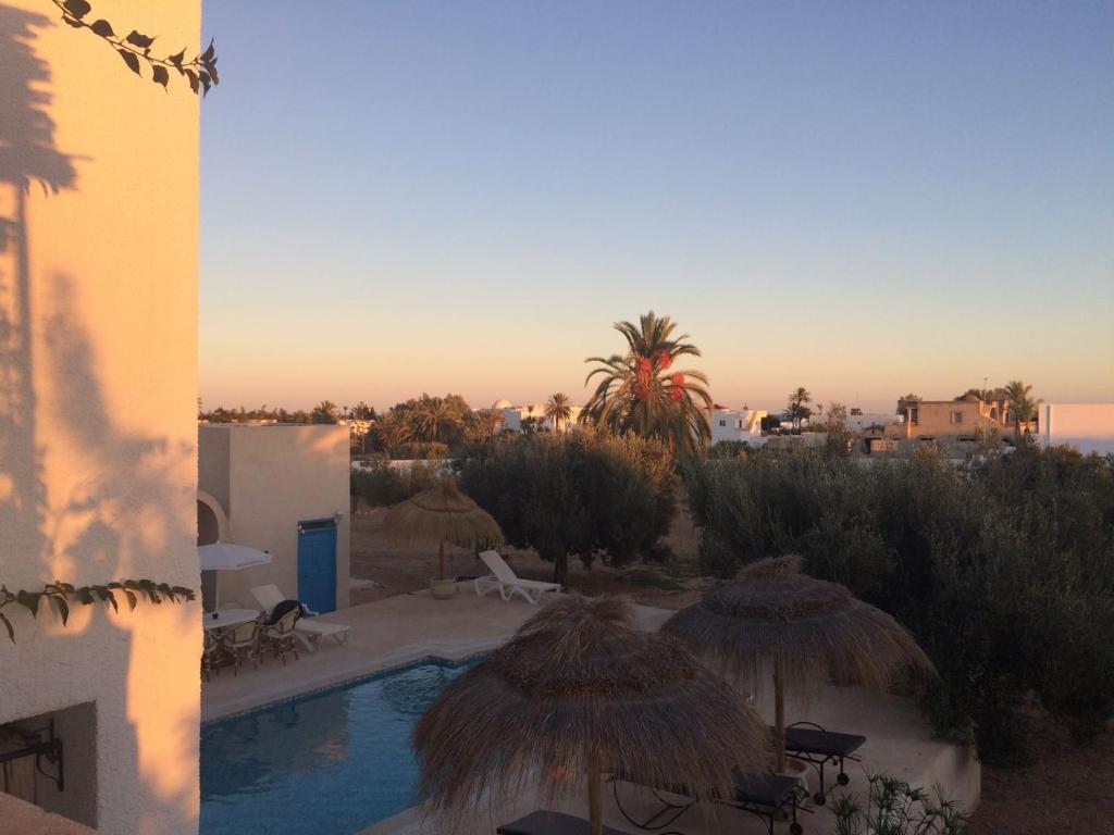 a view of a pool with umbrellas and a resort at Menzel Churasco Djerba in Aghīr