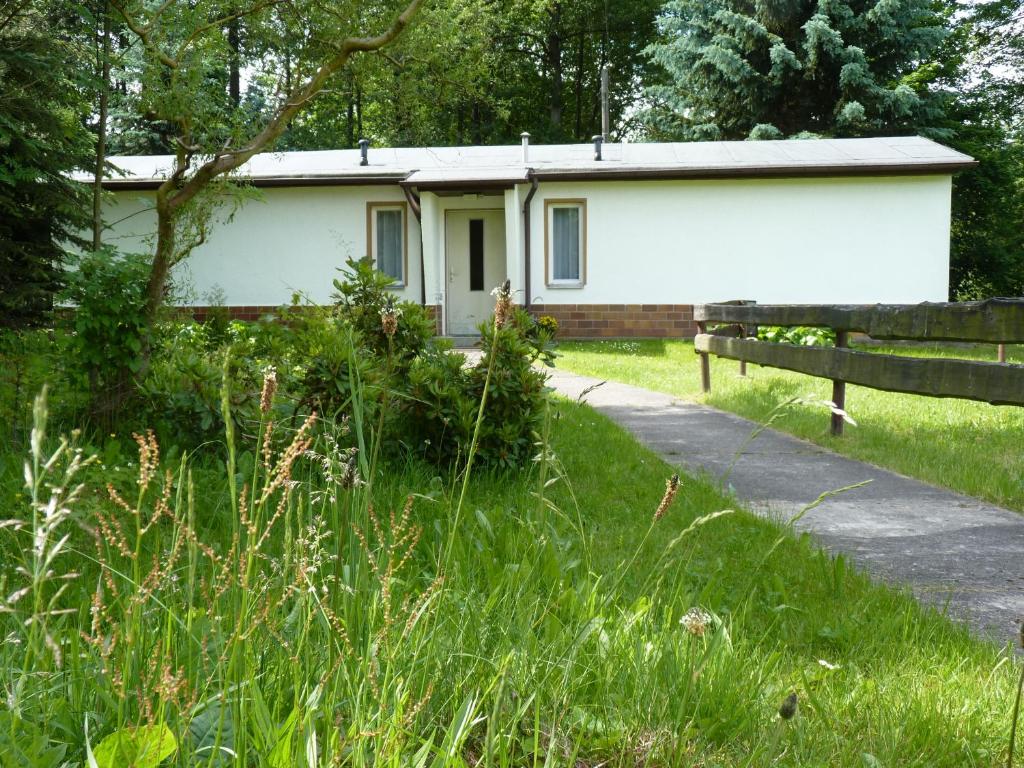 un petit bâtiment blanc dans un champ d'herbe dans l'établissement Haus Am Friedrichsbach, à Pöhla