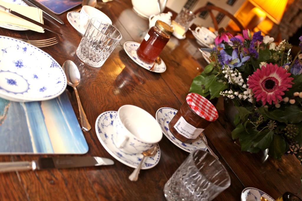 a wooden table with plates and a vase of flowers at Knockaloe Beg Farm in Patrick