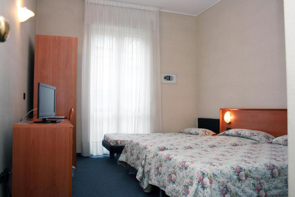 una camera d'albergo con due letti e una televisione di Hotel Engadina a Como