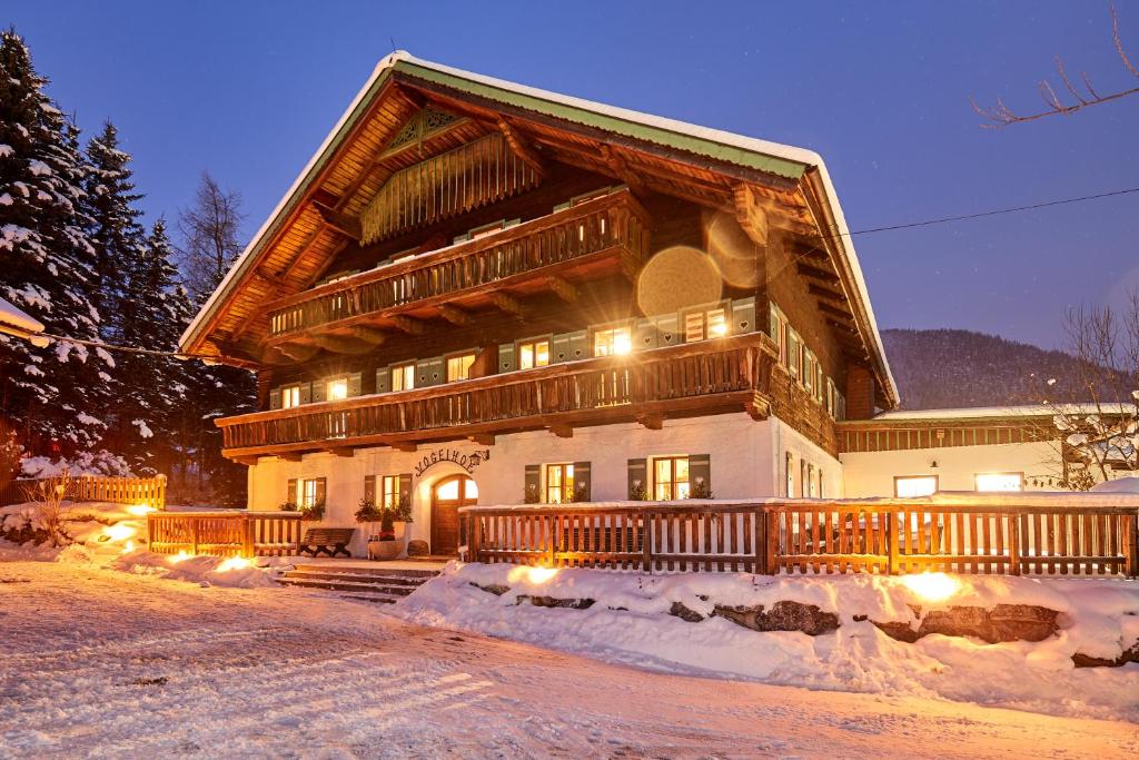 ein großes Holzhaus mit Schnee davor in der Unterkunft Gut Vögeihof in Forstau