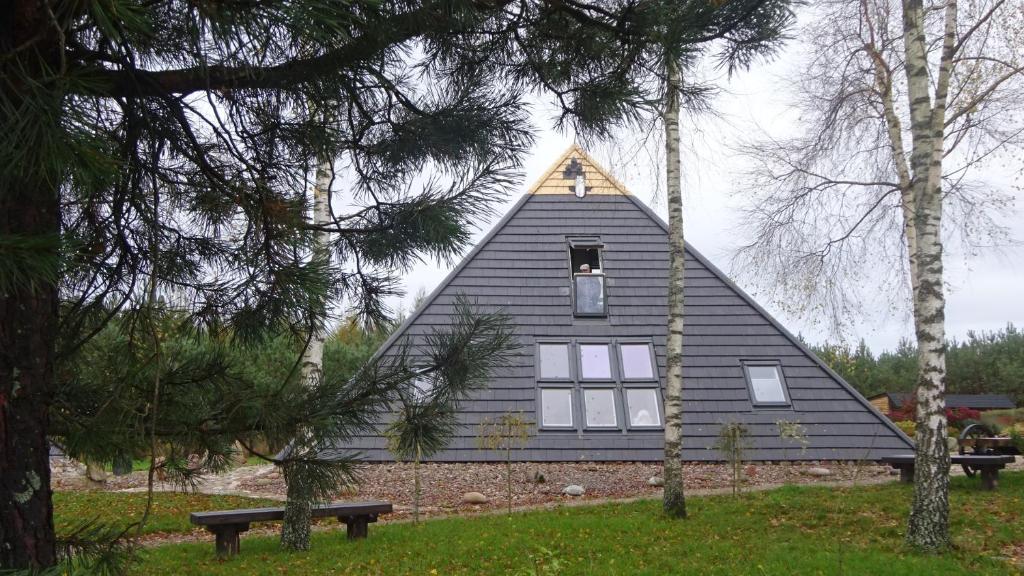 une maison noire avec un toit triangulaire dans un parc dans l'établissement TuDobrze Noclegi w piramidach, à Borzytuchom