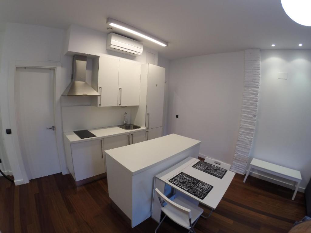 ログローニョにあるApartamentos Céntricos y Modernosの白いキャビネット、テーブルと椅子付きのキッチンが備わります。
