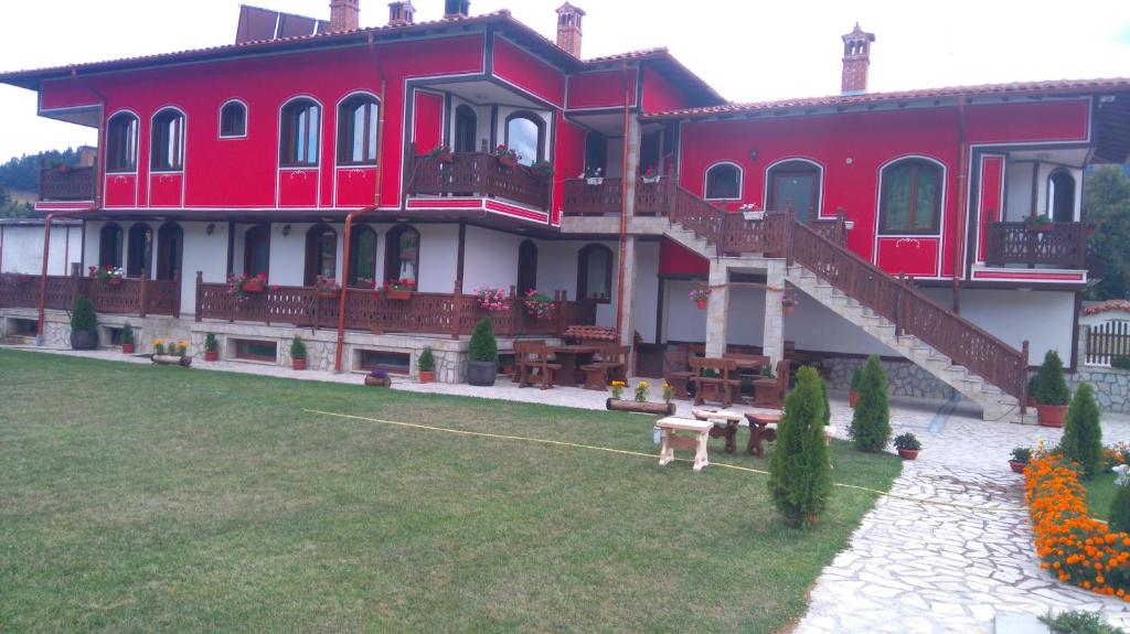 a large red building with stairs and a yard at Guest House H Dzhogolanov in Koprivshtitsa