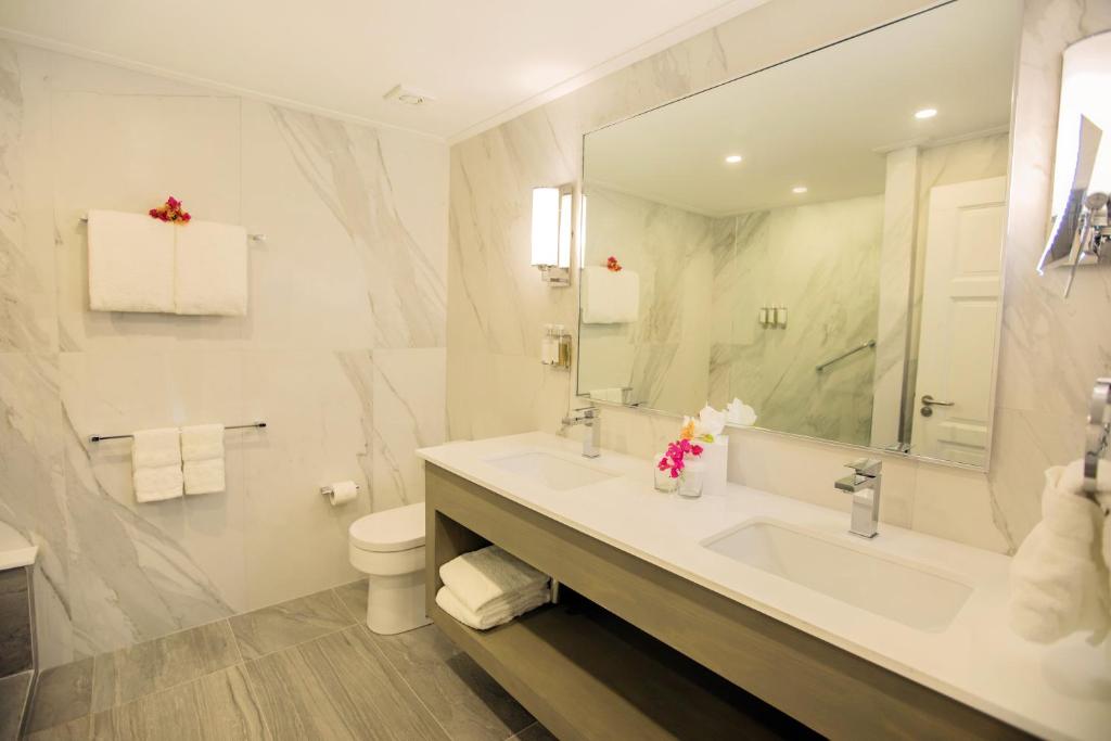 a bathroom with a sink and a toilet and a mirror at Bougainvillea Barbados in Christ Church