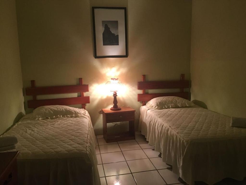 a bedroom with two beds and a lamp on a tiled floor at Nakum Hotel in Flores