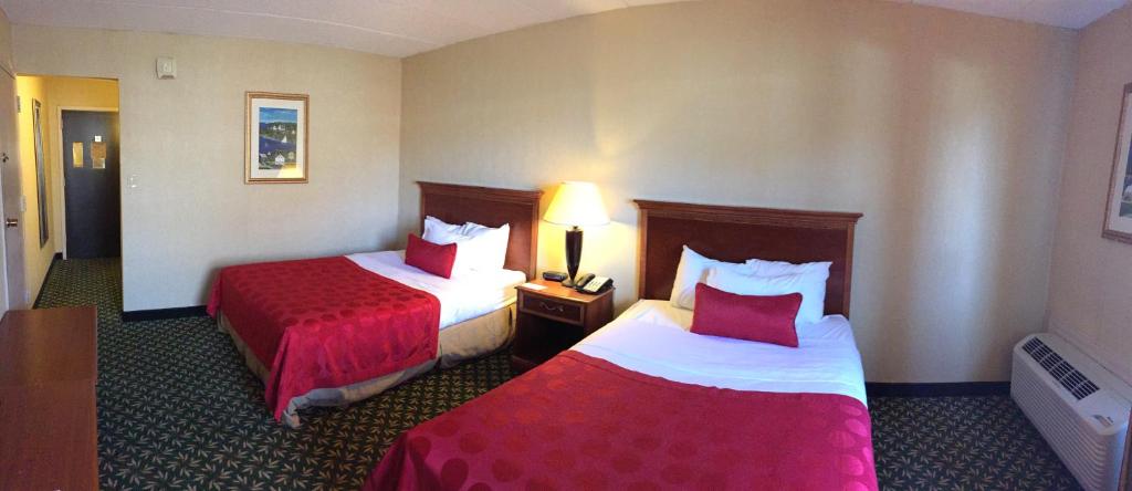 a hotel room with two beds with red sheets at Mystic River Hotel & Suites in Mystic