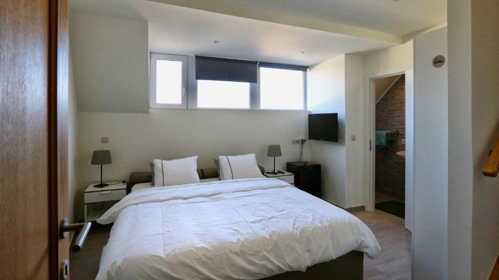 1 dormitorio con 1 cama blanca grande y 2 ventanas en B&B Handelshof en Lier