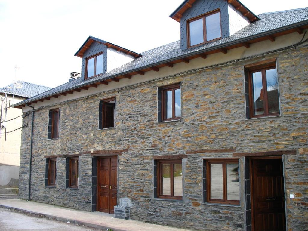 an old stone house with windows on a street at Brañuelas, Estacion 1 in Brañuelas