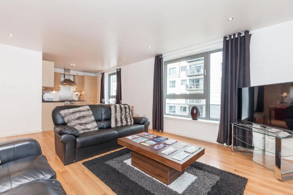 uma sala de estar com um sofá de couro e uma televisão em Stylish Apartment em Edimburgo