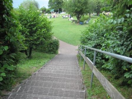 a brick path in a park with a fence at Seewohnung am Ossiacher See direkt an der Gerlitzen in Villach