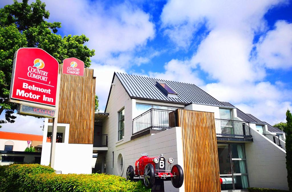 a house with a red sign in front of it at Belmont Motor Inn in Christchurch