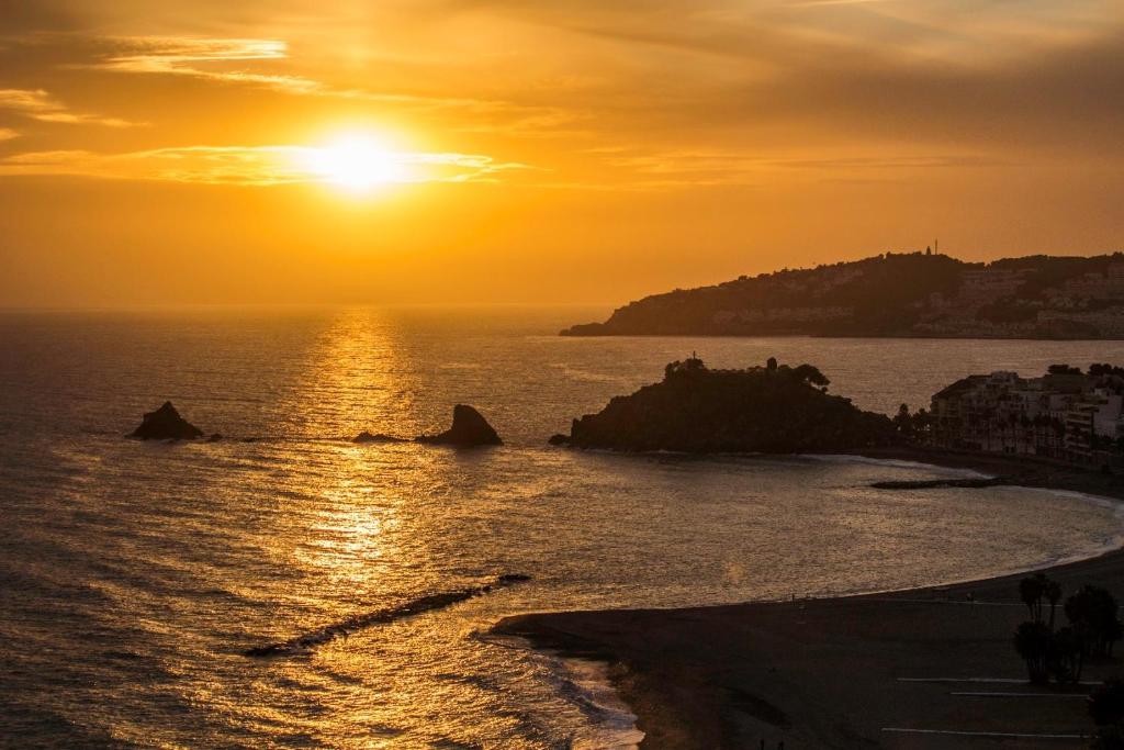 una puesta de sol sobre el océano con la puesta de sol en Urbanización las Gondolas, Espectaculares Vistas, en Almuñécar