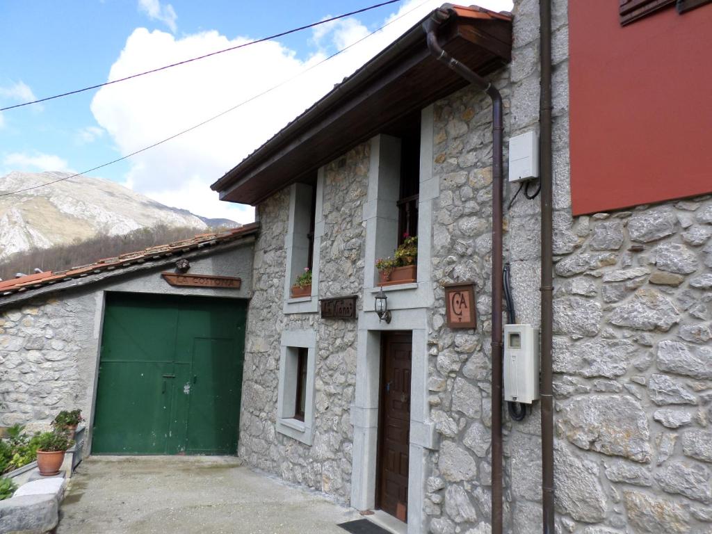 een stenen huis met een groene deur en een garage bij La Xiana in Taranes