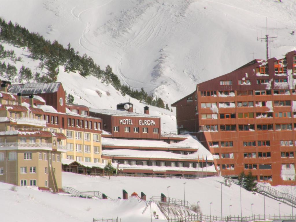 un grupo de edificios en la nieve con una montaña en Hotel Europa, en Astún
