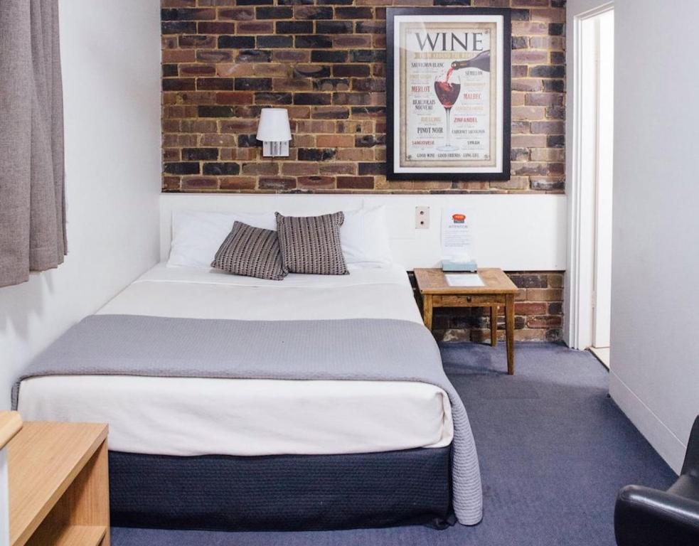 a bedroom with a bed and a brick wall at Hornsby Inn in Hornsby
