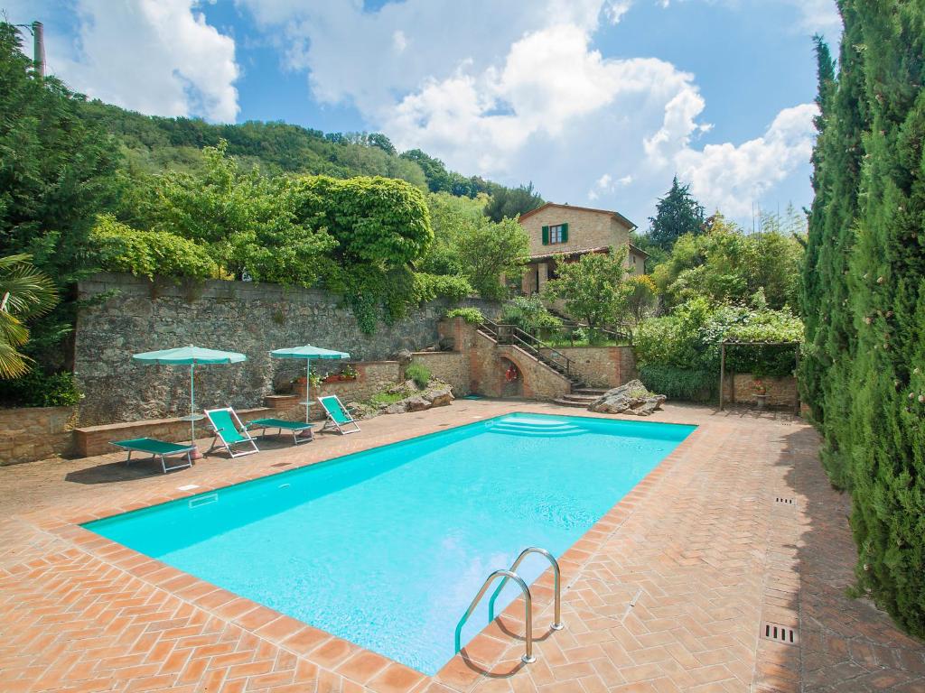 a swimming pool with two chairs and a house at Holiday Home Le Pergole by Interhome in Volterra