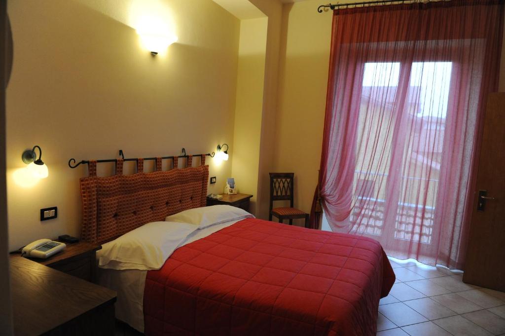 a bedroom with a red bed with a red blanket at Hotel Rossi in Manciano