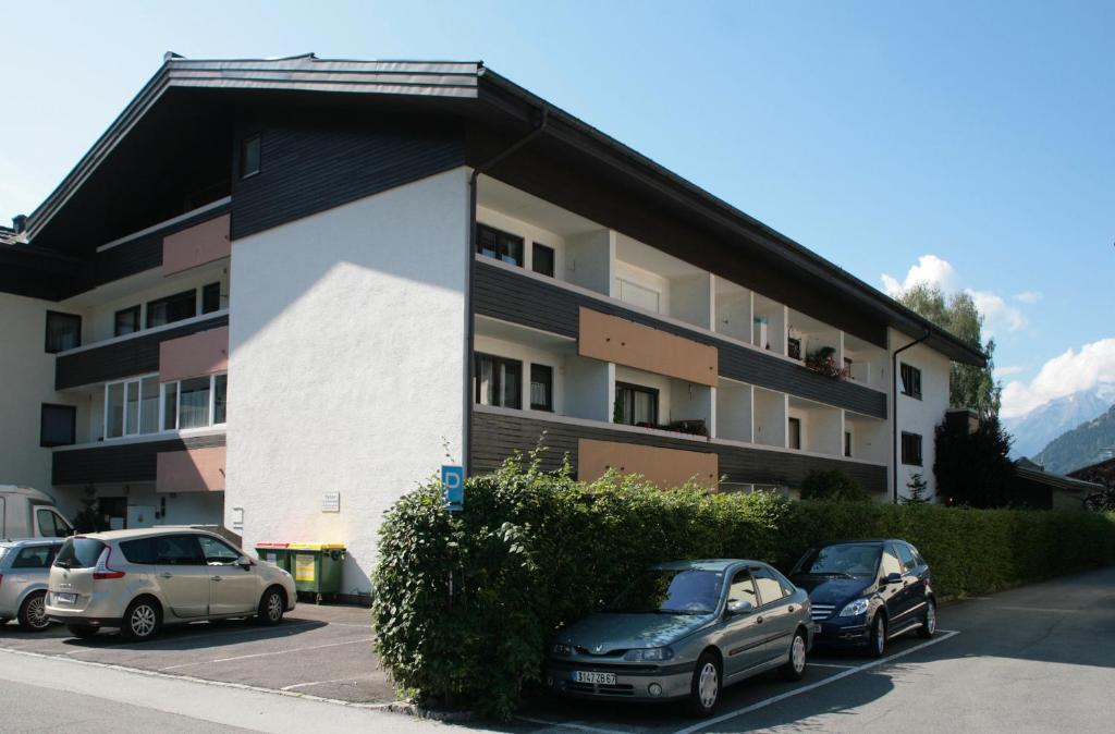 2 voitures garées sur un parking en face d'un immeuble dans l'établissement Appartement René, à Zell am See