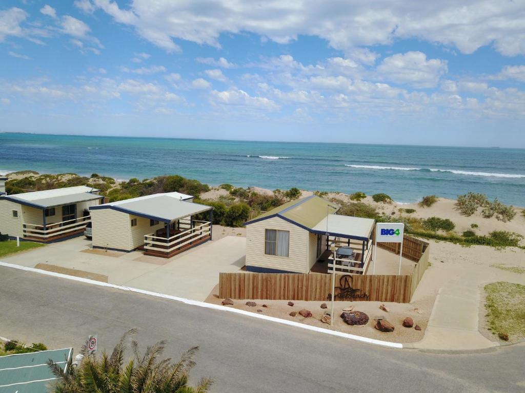 a beach scene with a house and a boat at Sunset Beach Holiday Park in Geraldton