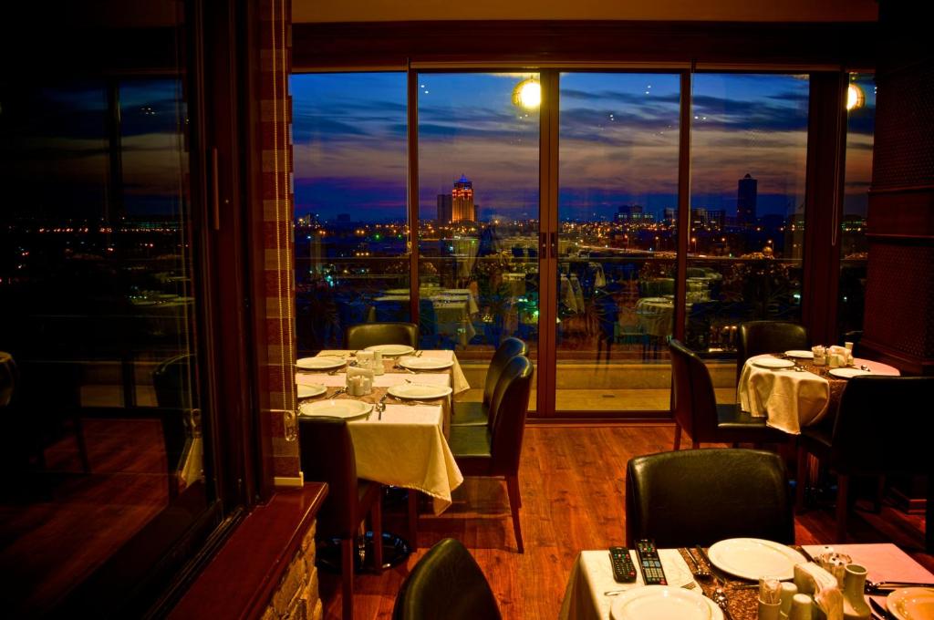 un restaurante con mesas y sillas y vistas a la ciudad en BL Hotel's Erbil, en Erbil