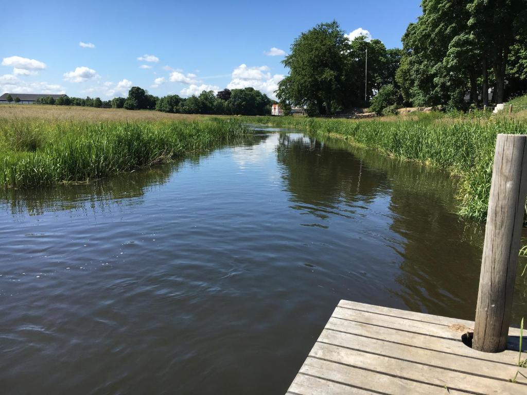 Un río con un muelle de madera en el agua en Kongeåkroen en Brørup