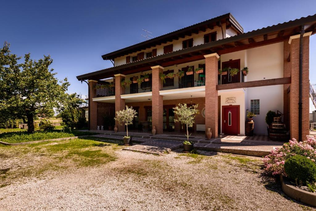 a large building with a red door and a yard at Agriturismo Nonis in San Vito al Tagliamento