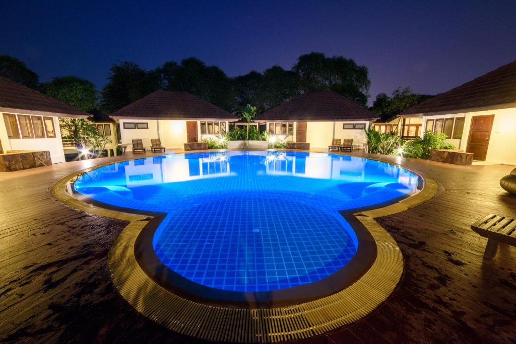 a large swimming pool lit up at night at Baan Suan Nuanta in Samut Songkhram