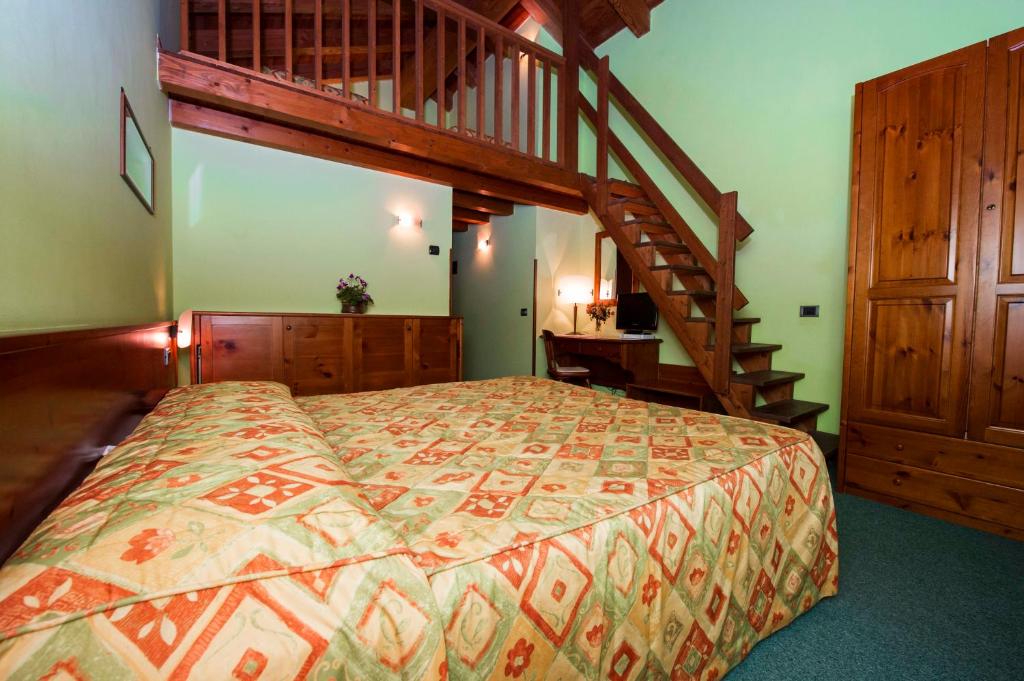 1 dormitorio con 1 cama grande y escalera de madera en Hotel Beau Site, en Brusson