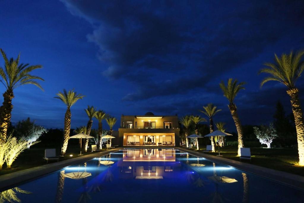 a villa with a swimming pool at night at Adnaa - Modern Villa with 2 pools, sauna, hammam, tennis court & home cinema in Douar Caïd Layadi