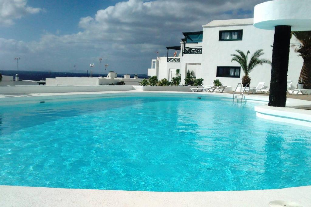 a large blue swimming pool in front of a house at APARTAMENTO CHAO PORTONOVO in Puerto del Carmen