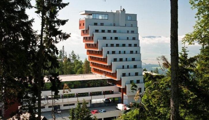 a tall building with a parking lot in front of it at Apartman Panorama 1001 in Vysoke Tatry - Strbske Pleso