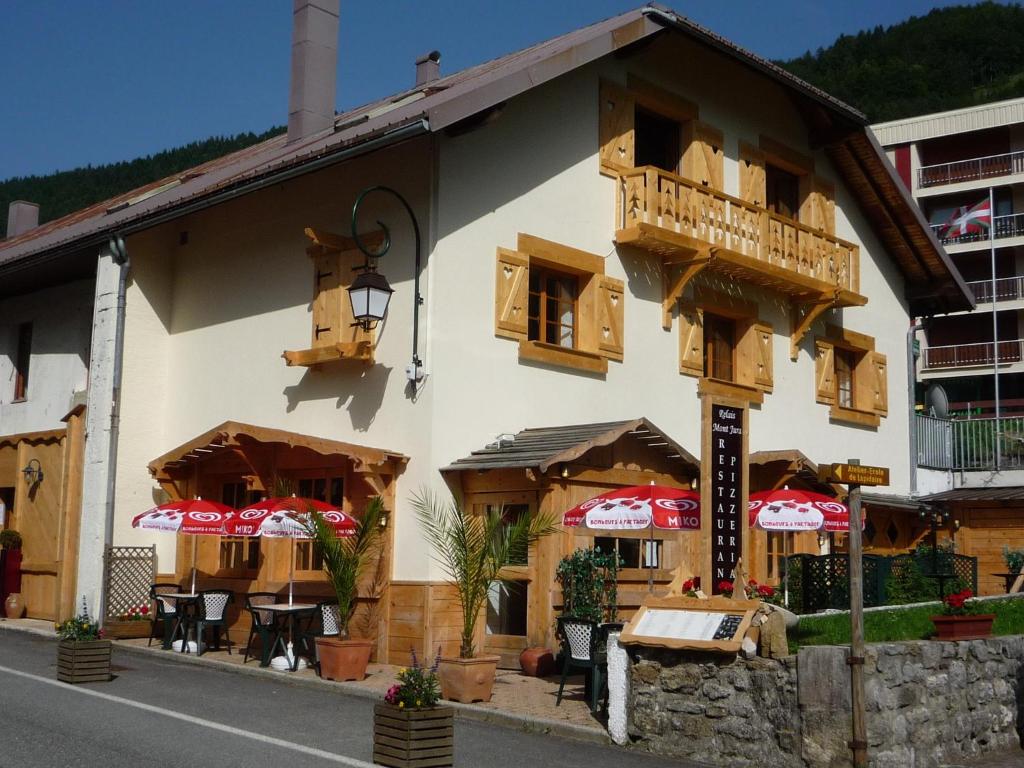 un bâtiment avec des tables et des parasols dans une rue dans l'établissement Relais Mont Jura Adults Only, à Lélex