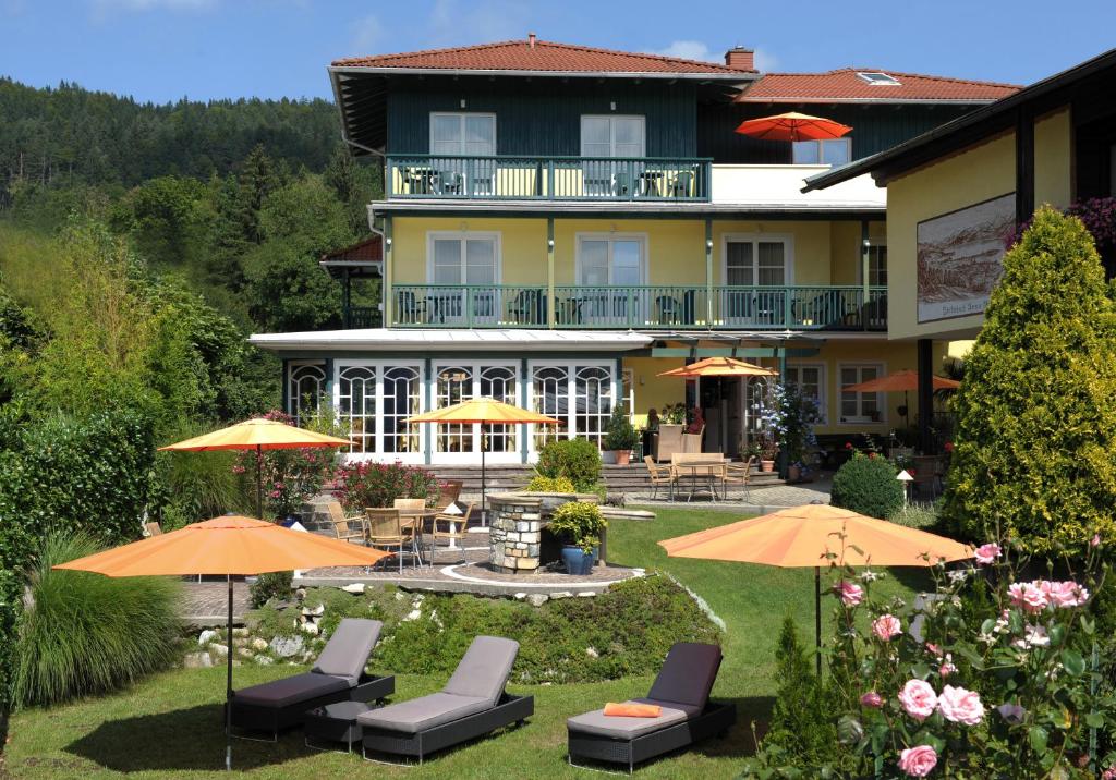un hotel con sillas y sombrillas en el patio en Die WUNDER s Ferienpension, en Pörtschach am Wörthersee