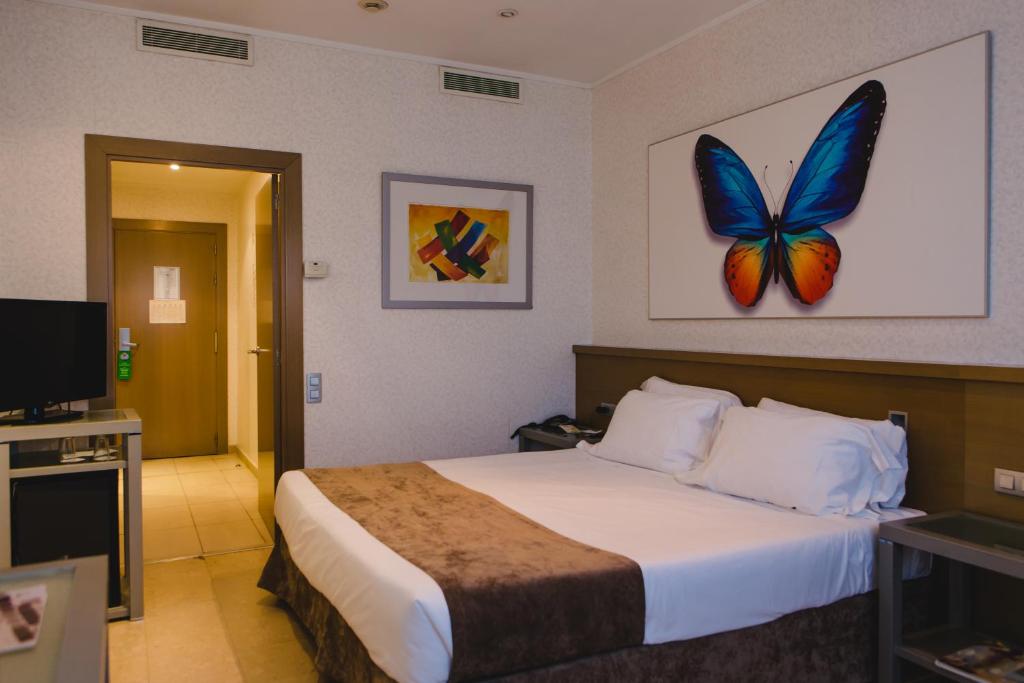 ein Hotelzimmer mit einem Bett mit einem Schmetterling an der Wand in der Unterkunft Hotel Mas Camarena in Paterna