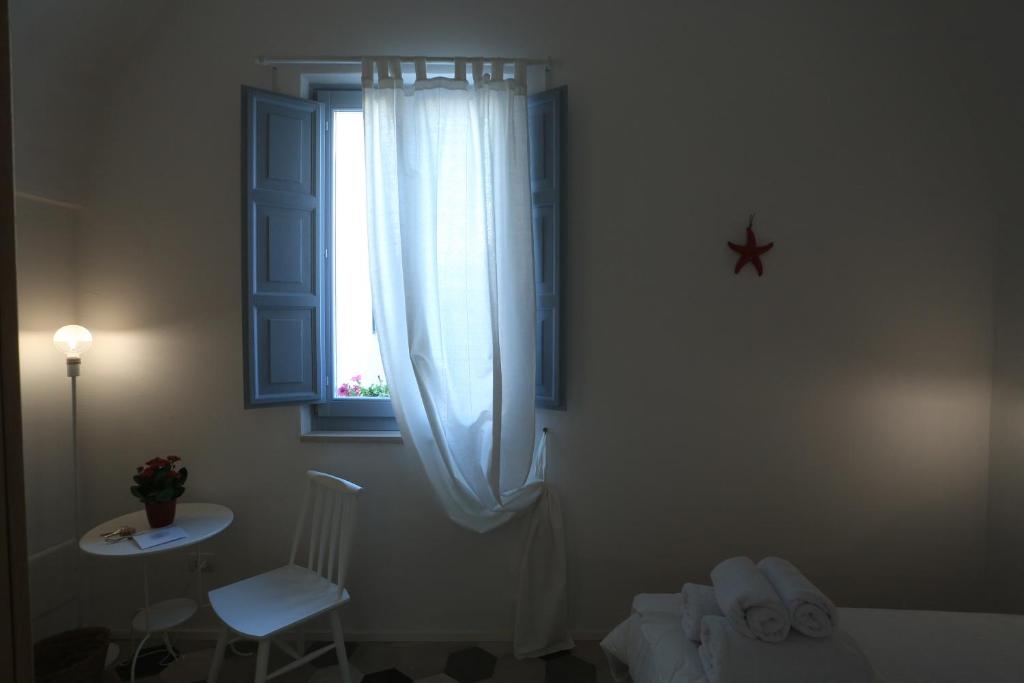 a bedroom with a window and a chair and a table at FONTEblu B&B in Polignano a Mare
