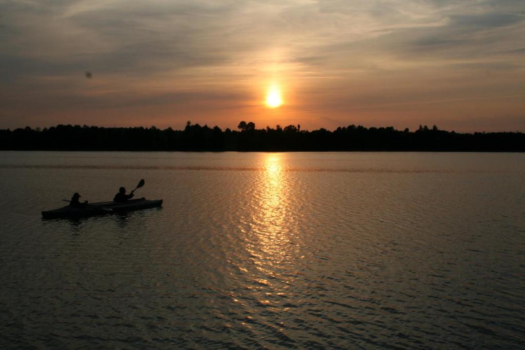 two people in a boat on a lake at sunset at Guest house Oaze in Miglāni