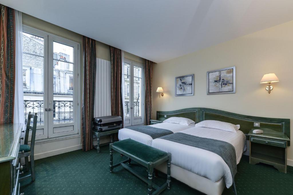 two beds in a hotel room with two windows at Hotel du Pré in Paris